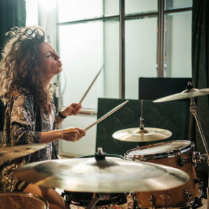 Woman playing drums during music band rehearsal