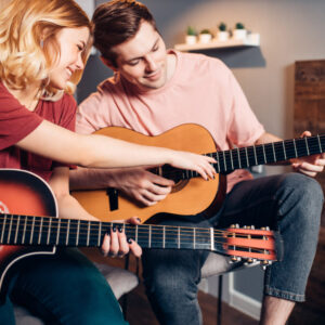 young caucasian female show how to play the guitar